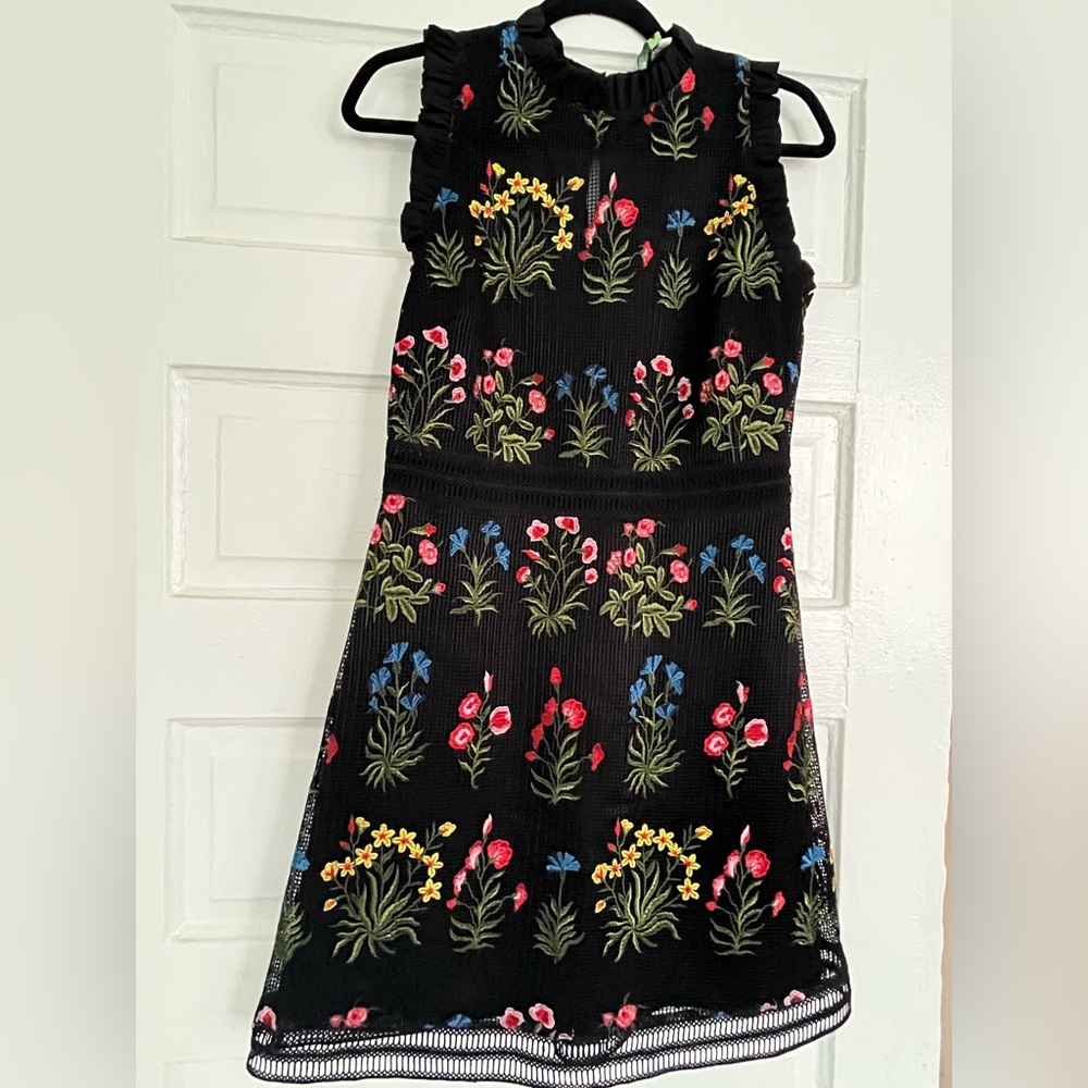 Lucy Paris black sleeveless mini dress embroidered with colorful flowers.